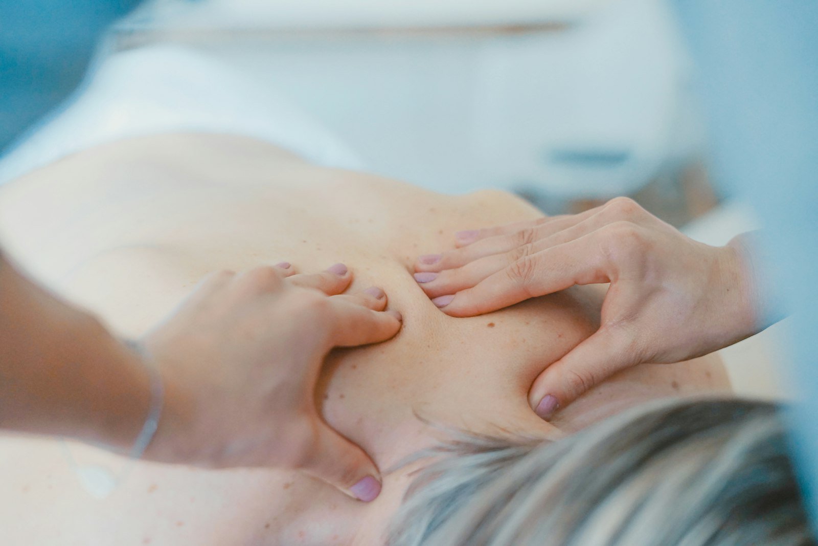 Fisioterapeuta explorando la espalda de una paciente en consulta